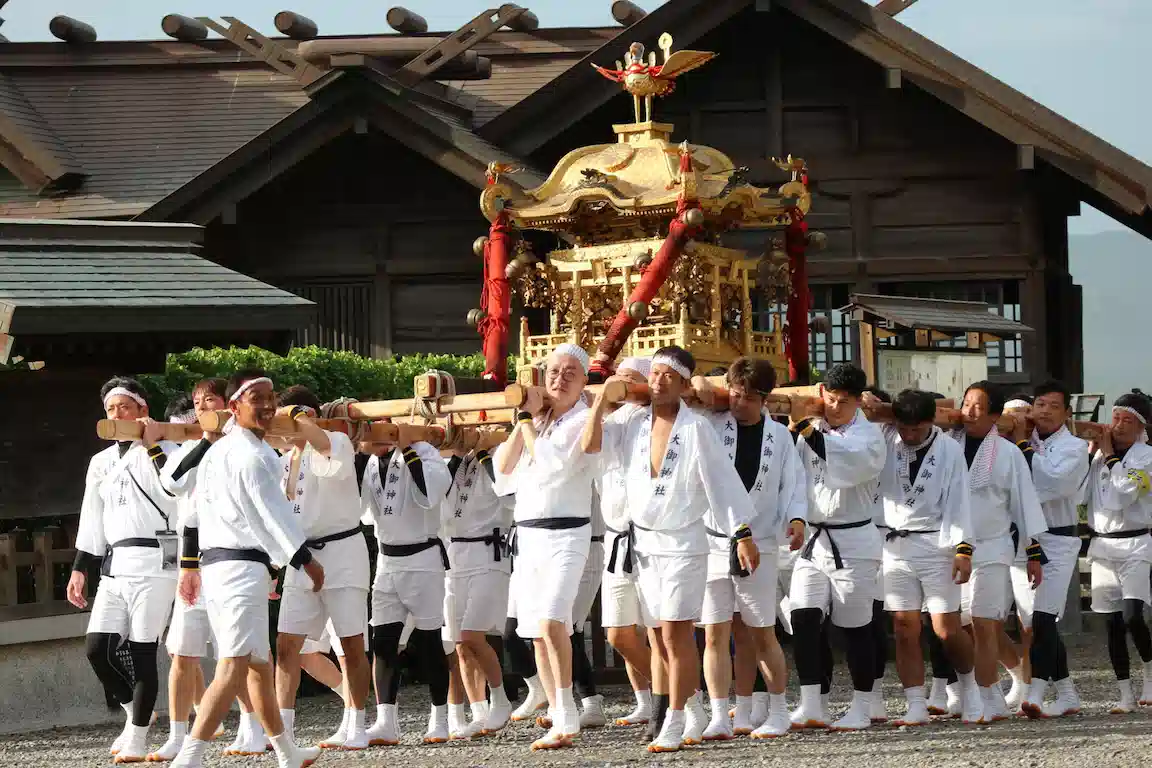 大御神社の境内から外へお神輿を運び出す厄年会の担ぎ手たち